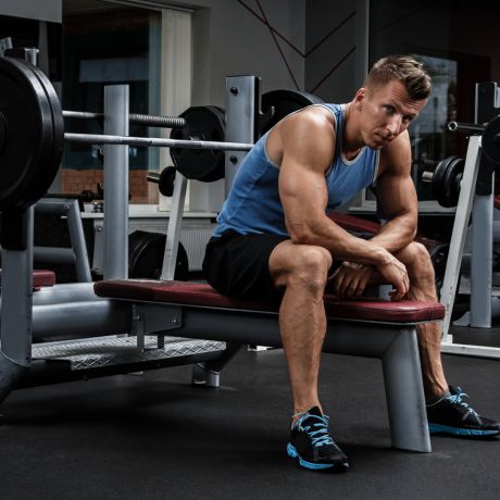 man sitting on a bench with heavy weights